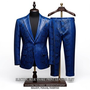 May include: An electric blue snake print leather suit, including a blazer and trousers, displayed on a mannequin and a hanger. The suit features a textured pattern and is custom tailored. The text on the base reads "ELECTRIC BLUE SNAKE PRINT LEATHER SUIT".