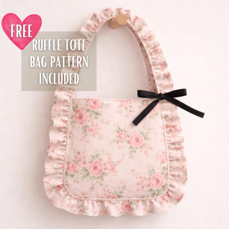 May include: A pink floral tote bag with a ruffle trim and handle. The bag features a black bow and the text "FREE RUFFLE TOTE BAG PATTERN INCLUDED" on the upper left corner. The bag is hanging on a wooden peg.