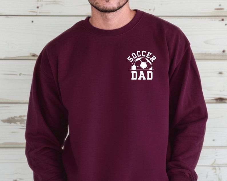 Pu&ograve; includere: Felpa bordeaux con la scritta bianca "Soccer Dad" e una grafica di pallone da calcio. La felpa girocollo a maniche lunghe &egrave; in tinta unita. Un capo casual per gli appassionati di calcio.