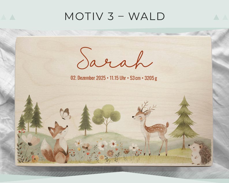 May include: A wooden box with a forest-themed illustration. The design includes a fox, deer, hedgehog, trees, and flowers. The name "Sarah" is written in cursive, along with the date, time, and measurements: 53 cm and 3205 g.
