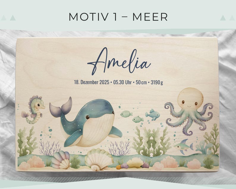 May include: Wooden box with a watercolor illustration of a whale, seahorse, octopus, and fish. The name "Amelia" is written in cursive, along with the date, time, length (50 cm), and weight (3190 g). The box has a light wood grain.