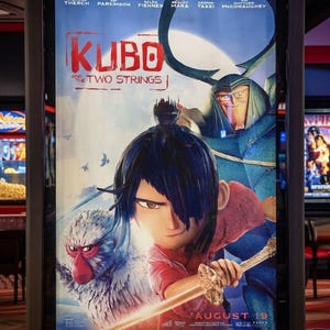 K&ouml;nnte beinhalten: Kinoplakat f&uuml;r den Film "Kubo - Der Zauber der zwei Saiten". Das Poster zeigt eine junge Figur mit schwarzen Haaren und einem Schwert, einen Affen und eine gro&szlig;e gepanzerte Figur. Der Titel ist rot, mit dem Erscheinungsdatum "19. August".
