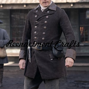May include: A dark brown double-breasted coat featuring a structured collar, long sleeves with brown cuffs, and two vertical rows of metallic buttons. A black leather belt with a metal buckle is worn at the waist, holding a black pouch and a knife.