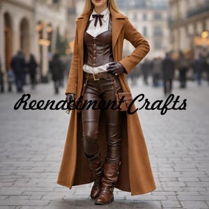 Op de afbeelding: Een lange, kameelkleurige jas gedragen over een bruin leren korset, een wit overhemd en een bruine leren broek. De outfit is gecombineerd met bruine leren handschoenen, laarzen en een kleine tas. De tekst "Reendstment Crafts" is in zwart cursief geschreven.