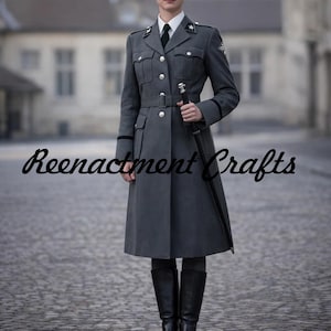 Può includere: Un cappotto grigio in stile militare con cintura in vita, dettagli di bottoni e dettagli neri. Il cappotto è indossato con una camicia bianca, cravatta nera e stivali neri. Il testo "Reenactment Crafts" è visibile.