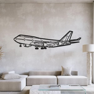 以下が含まれることがあります： 大型の旅客機をかたどった黒い金属製のウォールアート。機体、翼、エンジン、着陸装置の輪郭が詳細に描かれたシルエットで、無地の壁面に側面から見た姿で配置されています。