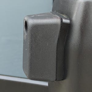 Puede incluir: Primer plano de un parachoques negro de vehículo con un componente de plástico negro que sobresale. El componente tiene un agujero cilíndrico y está fijado al parachoques. Se ve una luz trasera roja.