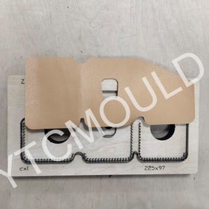 May include: A die-cut tool for leathercraft, featuring a light brown leather piece atop a wooden base. The base has a metal cutting edge and the text "225x97". The image also includes the text "YTC MOULD".