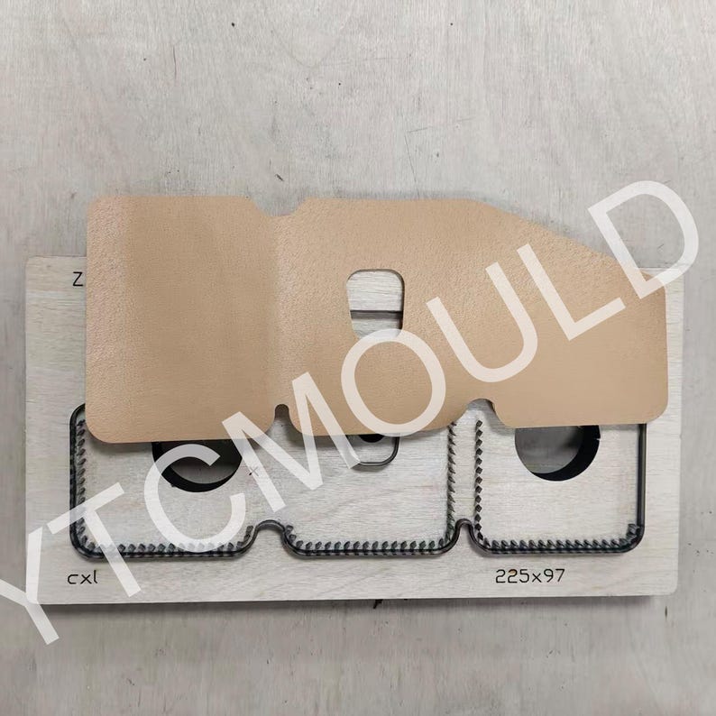 May include: A die-cut tool for leathercraft, featuring a light brown leather piece atop a wooden base. The base has a metal cutting edge and the text "225x97". The image also includes the text "YTC MOULD".