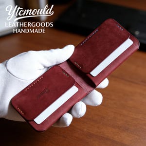 May include: Open burgundy leather wallet with white cards in the slots. The wallet is stitched with contrasting thread. The top left corner has the text "Ytcmould LEATHERGOODS HANDMADE".