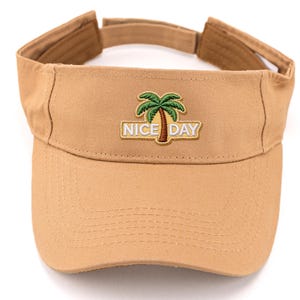 May include: Tan visor with a curved brim and adjustable strap. The front features an embroidered design of a palm tree and the words "NICE DAY". The visor is made of a durable fabric.