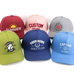 May include: Six baseball caps in various colors, including red, pink, and blue. Each cap features embroidered text and designs, such as "SUMMER," a baseball graphic, and "CAPTAIN." The caps have a mesh back for breathability.