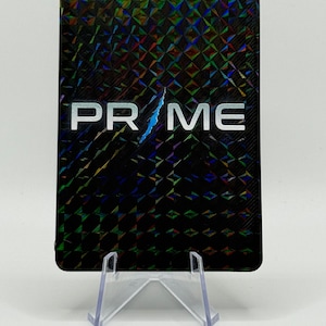 May include: A rectangular card featuring a black holographic background with a repeating diamond pattern. The word PR ME is printed in white capital letters across the center, with a jagged blue lightning bolt graphic replacing the letter I.