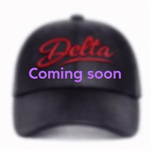 May include: Black baseball cap with the word "Delta" in red script and the words "Coming soon" in purple. The cap has a curved brim and a rounded crown. The background is white.
