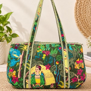 May include: A quilted tote bag featuring a dark green background with a vibrant jungle print, including pink flowers, green foliage, and a central illustration of a woman with parrots. The bag has two green and white striped fabric shoulder straps.
