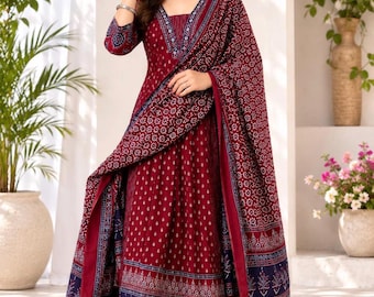 May include: A deep maroon Anarkali suit featuring a white geometric print, a V-neckline, and three-quarter sleeves. The ensemble includes matching wide-leg trousers and a long, coordinating dupatta with a dark blue border and intricate floral patterns.