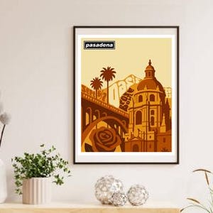 May include: Framed art print featuring a stylized illustration of Pasadena, California. The artwork showcases a bridge, a rose, palm trees, and a domed building in shades of brown and tan, with the word "Pasadena" at the top.
