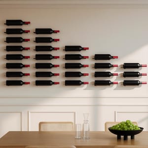 May include: A wall-mounted wine rack displaying numerous black wine bottles with red corks. The bottles are arranged in a visually appealing pattern against a white wall. The rack is designed to hold multiple bottles, showcasing a wine collection.