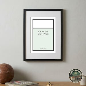 May include: A framed wall art print featuring a minimalist graphic design with a pale green rectangular block, a white top section, and black borders. The text reads CRAVEN COTTAGE and SW6 6HH in a clean, sans-serif black font centered within the design.