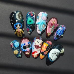 May include: A collection of ten uniquely designed artificial nails. Each nail features intricate, colorful designs, including a character, an octopus, and other artistic elements. The nails are set against a dark background, showcasing the detailed nail art.