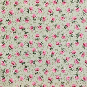 May include: A fabric with a repeating floral pattern. Small pink flowers with green leaves and stems are scattered across a light green background. The design is a classic, delicate floral print.