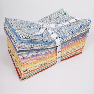 May include: A stack of colorful fabric squares, bound with a white measuring tape. The fabrics display various patterns, including floral and geometric designs in shades of blue, yellow, orange, and red. The measuring tape shows inch measurements.