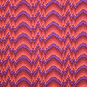 Puede incluir: Una tela con un patrón repetido de zigzags naranja, rojo y morado. El patrón crea un efecto de ilusión óptica ondulado.