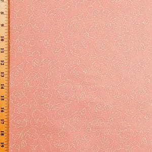 May include: A close-up of a pink fabric with a repeating pattern of white rose outlines. The fabric has a textured appearance and a ruler is visible along the left edge, showing measurements in inches.