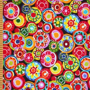 May include: Colorful fabric with a repeating pattern of circular floral designs in red, pink, yellow, green, and blue on a black background. The text "THE SPIN CYCLE" is visible. The fabric is measured with a wooden ruler.