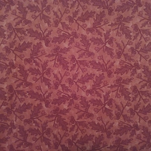 May include: A red fabric with a repeating pattern of dark red oak leaves and acorns.