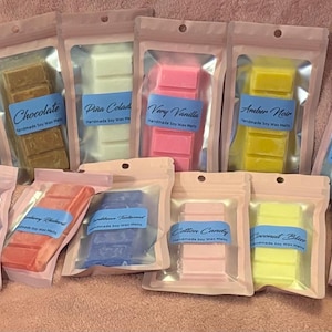 May include: Assortment of handmade soy wax melts in various colors and scents, including blue, brown, pink, yellow, and green. Each melt is packaged in a clear plastic bag with a label indicating the scent name, such as "Cool Water" and "Chocolate".