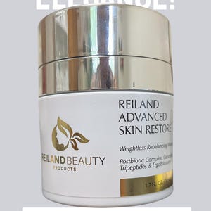 May include: A white and gold jar of Reiland Advanced Skin Restore cream. The jar has a silver lid and the text "ELEGANCE!" and "ELEVATE YOUR REGIMEN!" are displayed above and below the jar. The jar contains 1.7 fl oz.