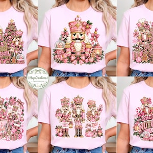 Può includere: Una t-shirt rosa chiaro con sei diversi disegni grafici di schiaccianoci nelle tonalità del rosa, oro e marrone. Le grafiche includono elementi festivi come alberi di Natale, regali e testi come 'Tis Season', 'Yall Are Nuts' e 'She Loves The Nutcracker I Can Tell'.