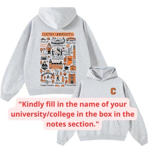 May include: A light gray hoodie with a hood and a front pocket. The back of the hoodie features a custom university design in orange and black. The front of the smaller hoodie has an orange "C".