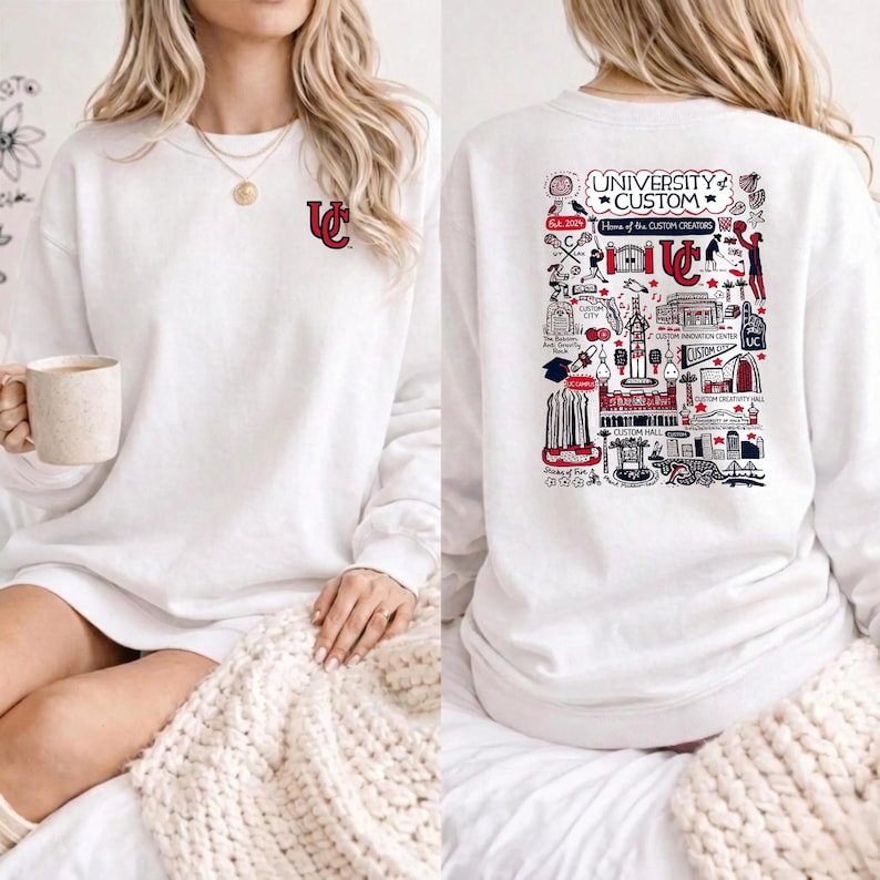 Puede incluir: Sudadera blanca con un peque&ntilde;o logotipo rojo y blanco en la parte delantera y un gr&aacute;fico detallado en la parte trasera. El gr&aacute;fico trasero incluye el texto "UNIVERSITY CUSTOM" y varias ilustraciones en rojo, blanco y negro.