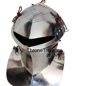 Op de afbeelding: Een gepolijste zilverkleurige metalen helm met een brede nekbeschermer. De helm heeft een afgeronde bovenkant en een donkere opening voor het gezicht. Leren riemen zijn aan de helm bevestigd. De tekst "Throne Treasure" is zichtbaar.