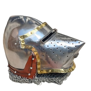 May include: A shiny steel helmet with brass detailing and a pointed visor. The helmet has small ventilation holes and a chainmail neck guard. A brown leather piece is riveted to the side. The helmet is a historical item.