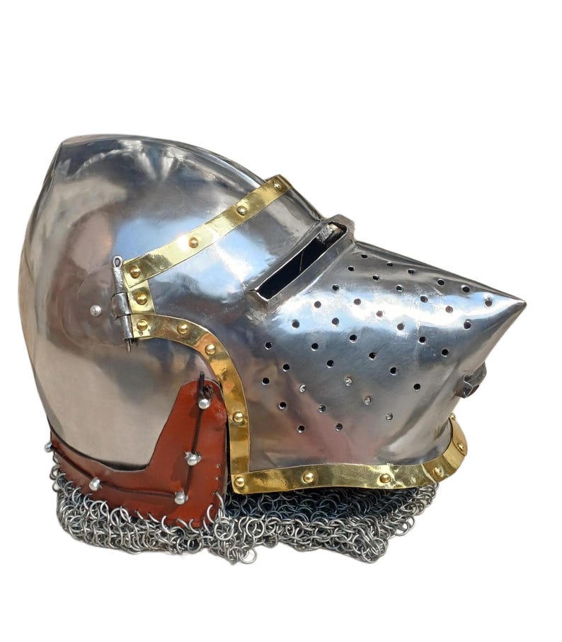 May include: A shiny steel helmet with brass detailing and a pointed visor. The helmet has small ventilation holes and a chainmail neck guard. A brown leather piece is riveted to the side. The helmet is a historical item.
