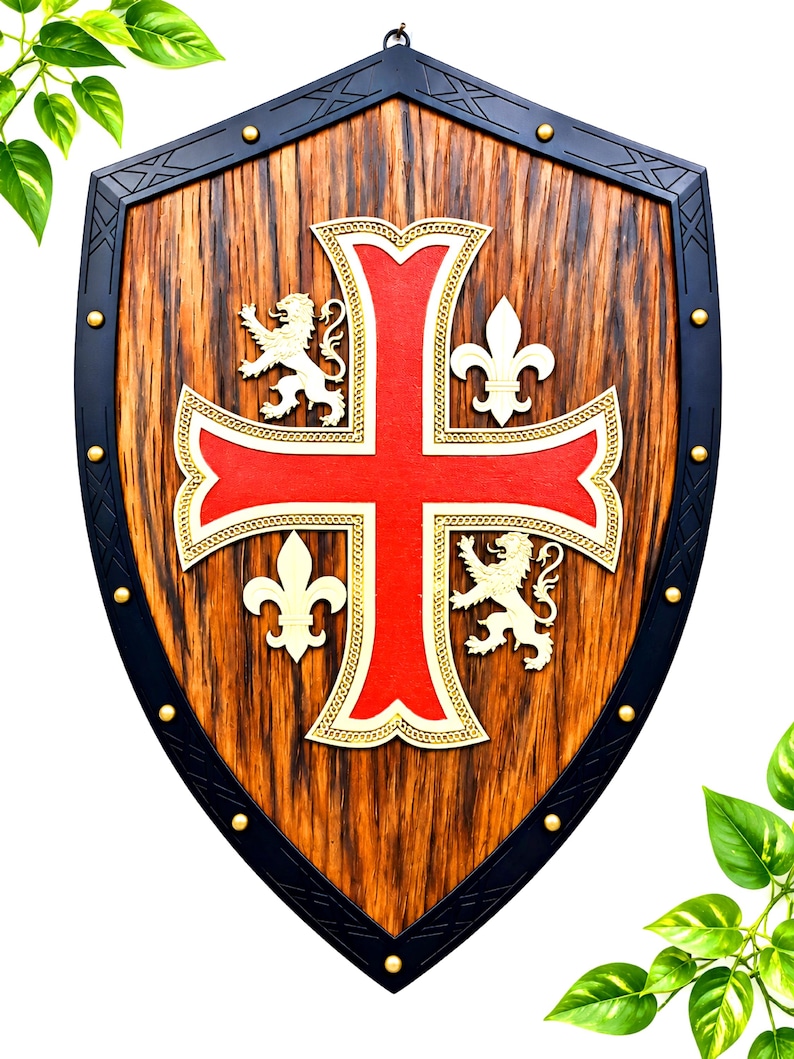 May include: A wooden shield with a dark wood grain finish and a black metal border featuring gold rivets. The center displays a large red cross with gold trim, flanked by two white lions and two white fleur-de-lis symbols on the wooden surface.