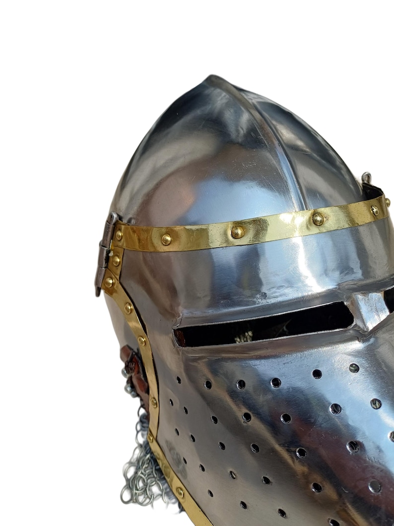 May include: A shiny, silver-coloured medieval helmet with a brass band around the brow, secured with rivets. The helmet has a visor with eye slits and small ventilation holes. A chainmail neck guard is present.
