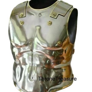 May include: A silver breastplate with gold detailing and rivets. The armour is curved to fit the torso and has a polished finish. The text "Throne Treasure" is visible. The breastplate is likely for historical reenactment.