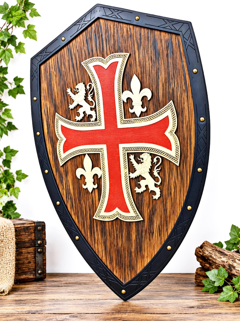 May include: A heater-style shield featuring a dark wood grain center with a prominent red cross outlined in gold. The shield includes two gold lion figures and two gold fleur-de-lis symbols. A black metal border with gold rivets frames the shield.