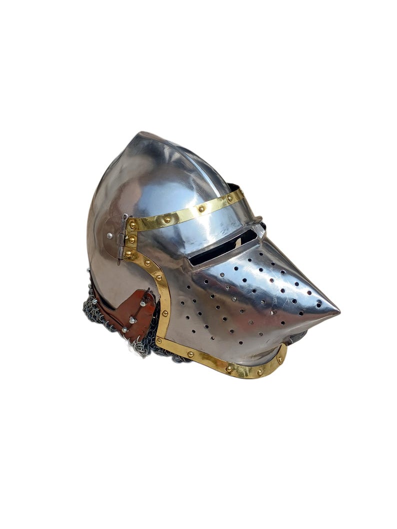 May include: A shiny steel helmet with a pointed visor and brass detailing. The helmet has small holes on the visor and a chainmail neck guard. The design is reminiscent of medieval armour.