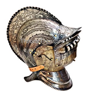 May include: An antique silver helmet with detailed etched patterns and brass rivets. The helmet has a visor, neck guard, and a leather chin strap. The surface of the helmet is decorated with elaborate designs.