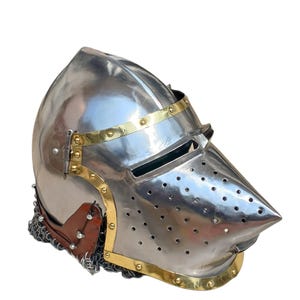 May include: A polished steel helmet with a pointed visor and brass detailing. The helmet has small ventilation holes and brass bands. A leather and chainmail neck guard is attached to the helmet.