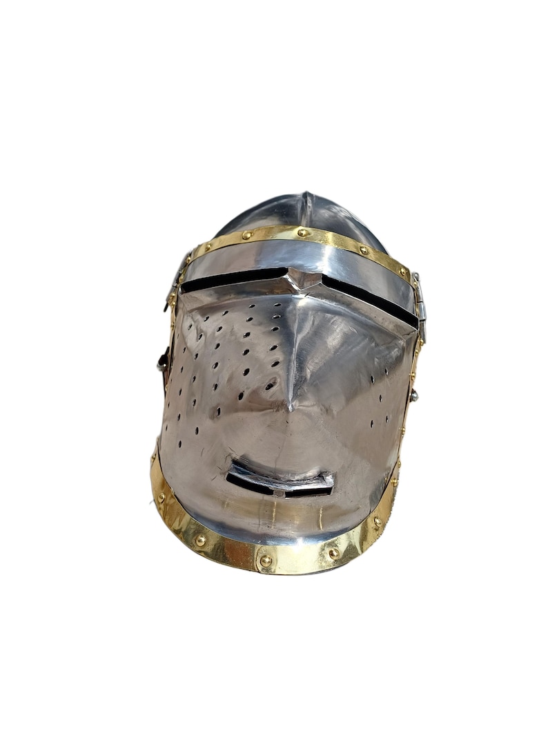 May include: A polished steel knight's helmet with brass detailing. The helmet has a visor with a horizontal slit and small ventilation holes. Brass bands adorn the brow and base, creating a historical aesthetic. The helmet is a classic piece of armour.