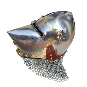 May include: A shiny steel helmet with a pointed visor, brass detailing, and a chainmail aventail. The helmet has a leather strap and rivets. This medieval-style helmet is suitable for historical reenactment or display.