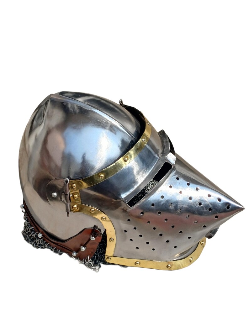 May include: A polished steel helmet with a pointed visor, brass detailing, and a chainmail neck guard. The helmet features a rounded crown and ventilation holes. The design is reminiscent of medieval armour.
