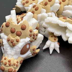 May include: A detailed, three-dimensional sculpture featuring a white base with tan and brown accents. The design incorporates rounded shapes and textured surfaces, creating a unique and artistic aesthetic. The sculpture's intricate details suggest a fantasy or abstract theme.
