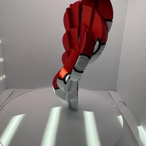 May include: A 3D-printed, red, white, and black decorative object, resembling a stylized sphere. The object is held up against a white background. The sphere is composed of several connected, circular segments.